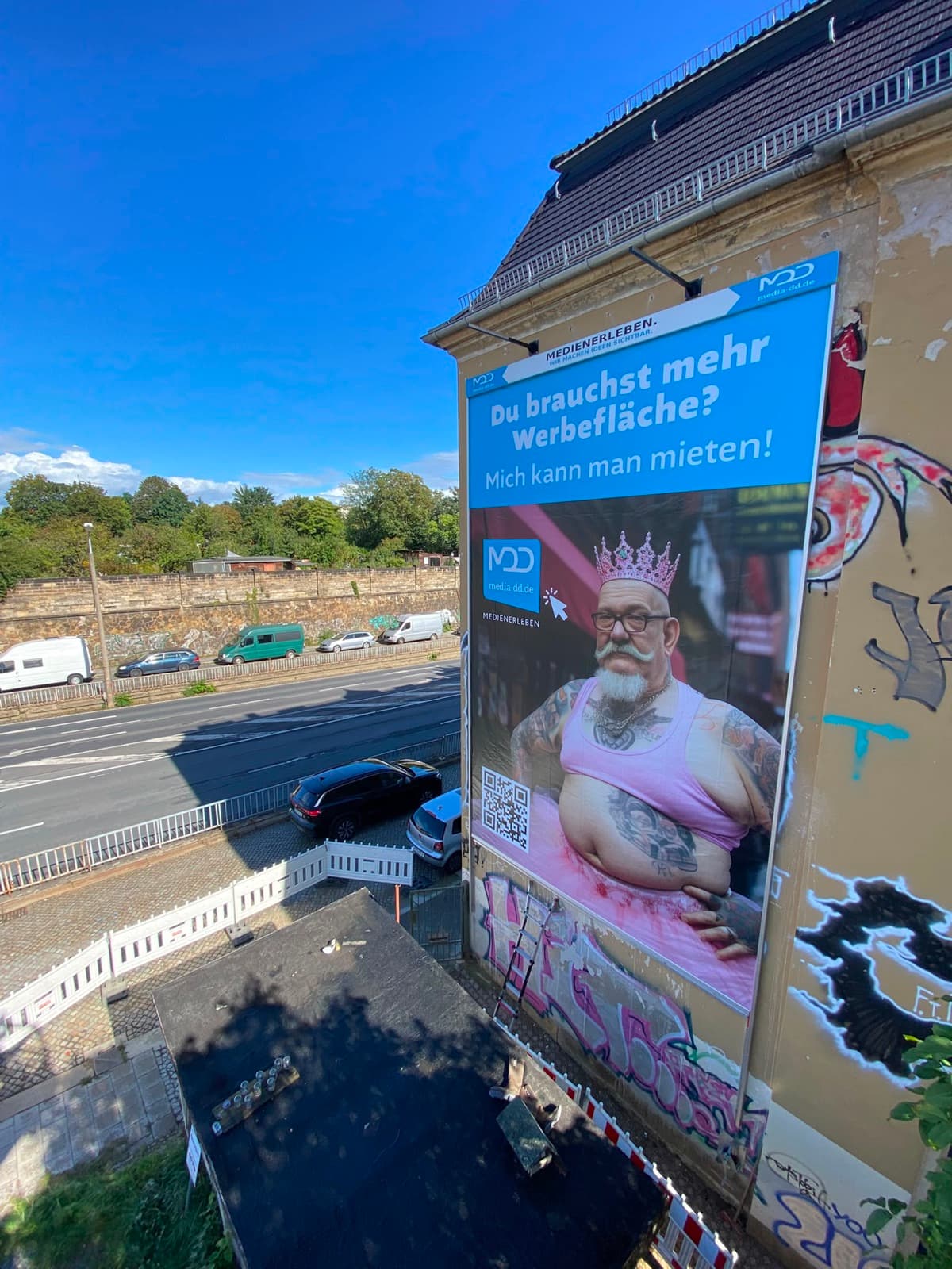 Hauswand in Dresden mit großformatigem Plakat: „Du brauchst mehr Werbefläche? Mich kann man mieten!“